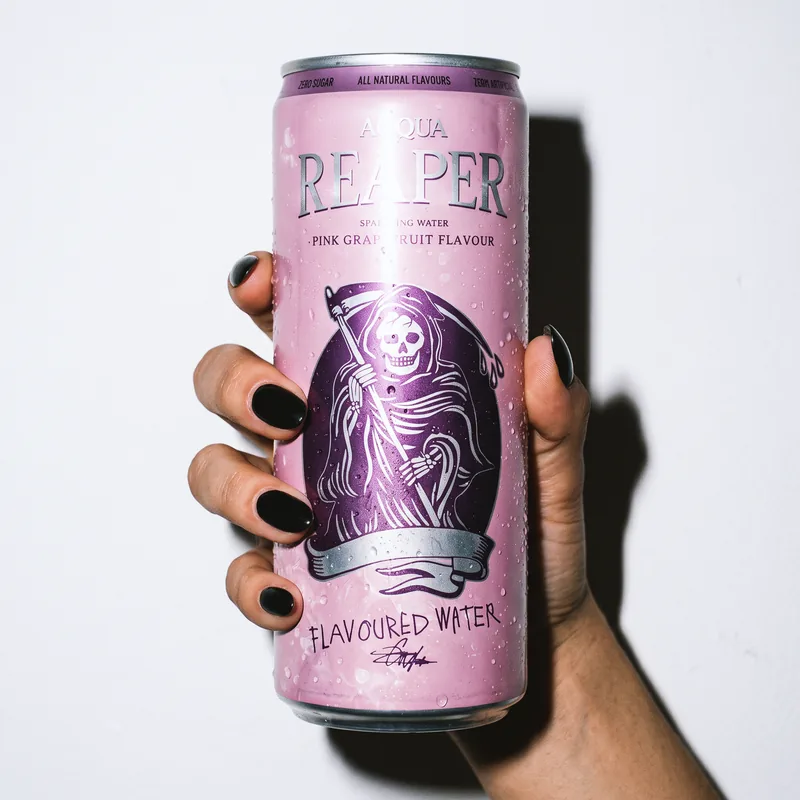 A hand with black nails is holding a can of Pink Grapefruit